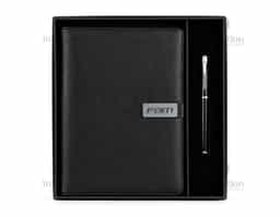 Kit executivo composto por dois itens: um caderno fichário e uma caneta. O caderno tipo fichário possui capa em couro sintético, fecho magnético e plaquinha metálica fixa à aba, mecanismo de argolas em aço carbono com abertura facilitada, aproximadamente 99 folhas de tamanho A5 pautadas em marfim com espaço para assinalar dias da semana e datas numéricas e interior da capa com compartimento para cartões e porta-canetas. A caneta metálica possui detalhes em plástico e carga esferográfica preta de 0,8 mm. Acompanha caixa em papelão com berço em PET com revestimento aveludado para acomodação dos itens.